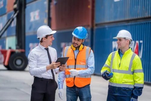 three workers in front of containers