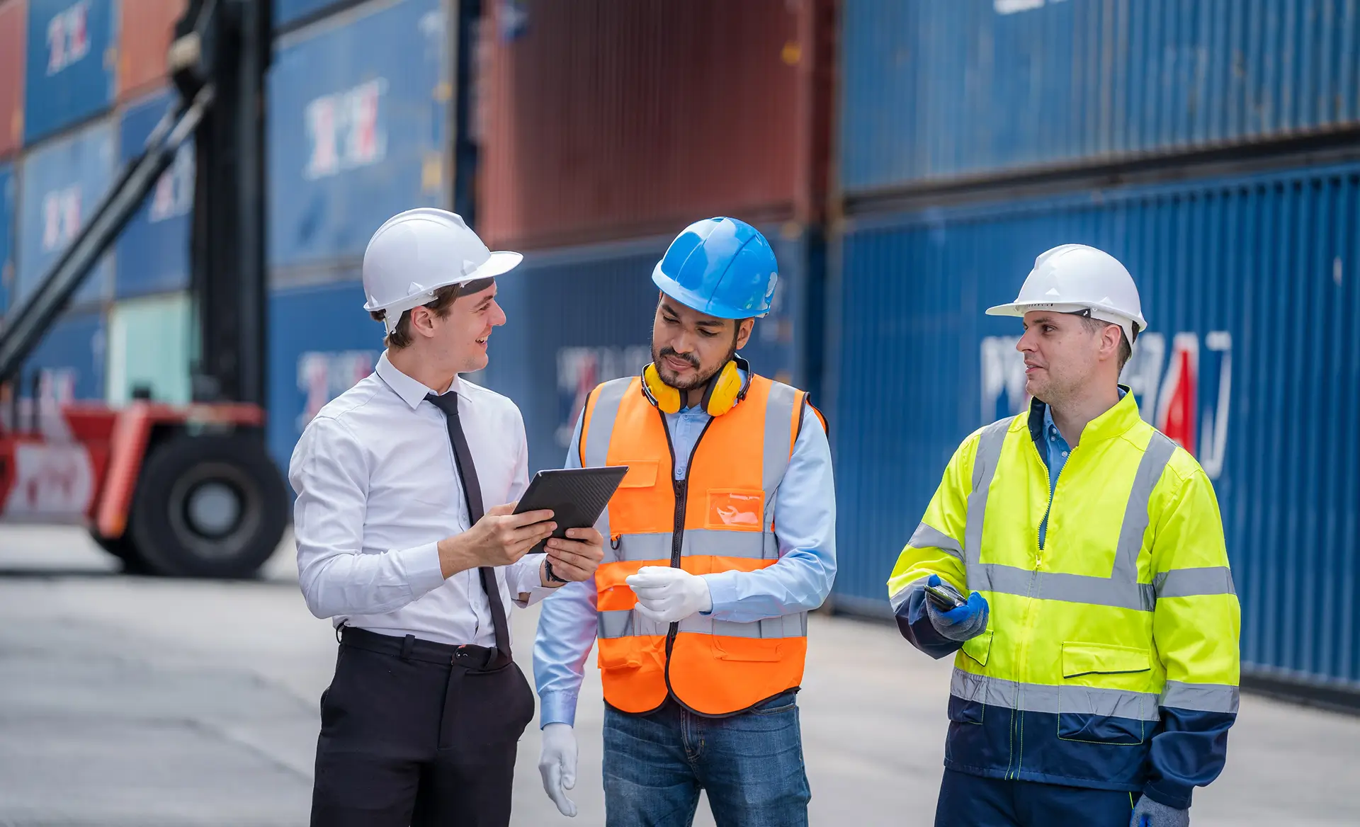 three workers in front of containers
