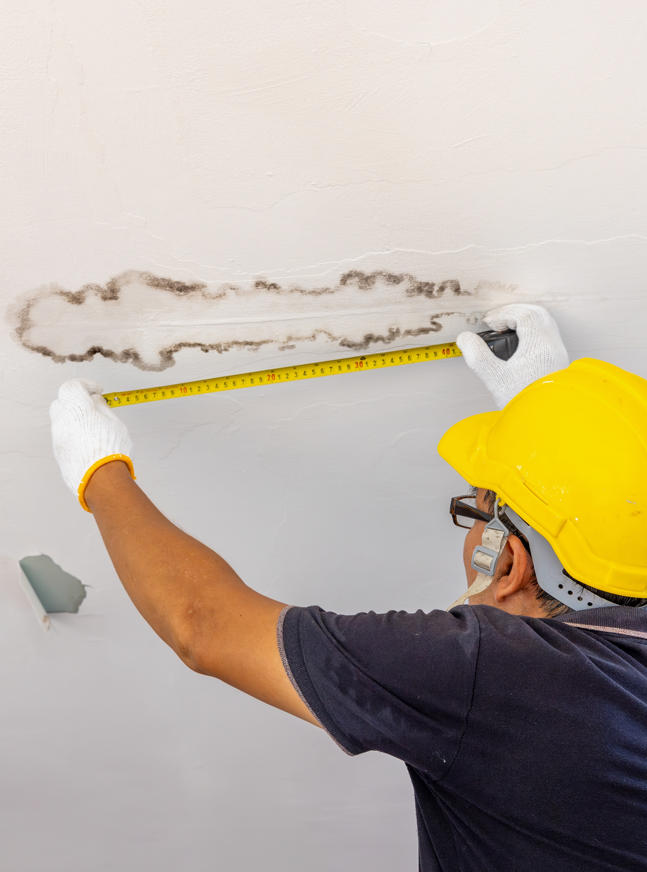 worker using tape measure over mold spot