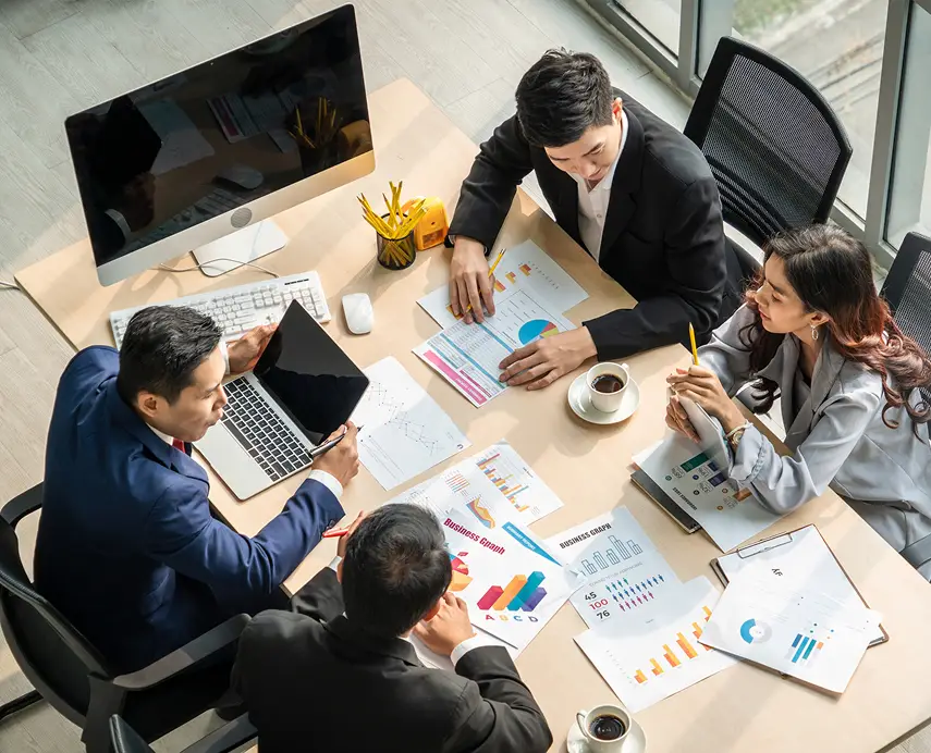 Office workers sitting at large desk having meeting