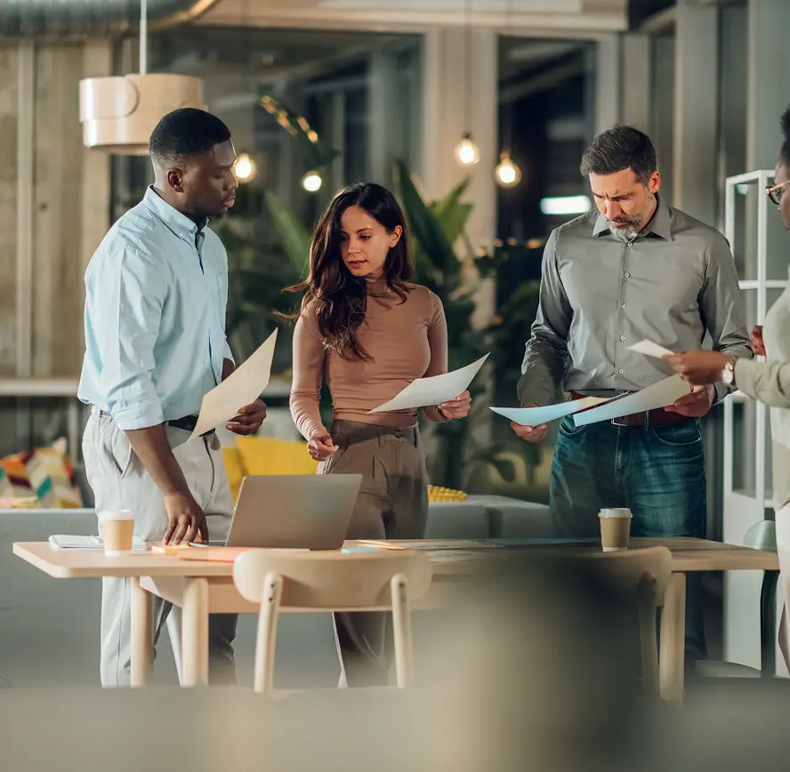 Group of 3 office workers all holding sheets of paper